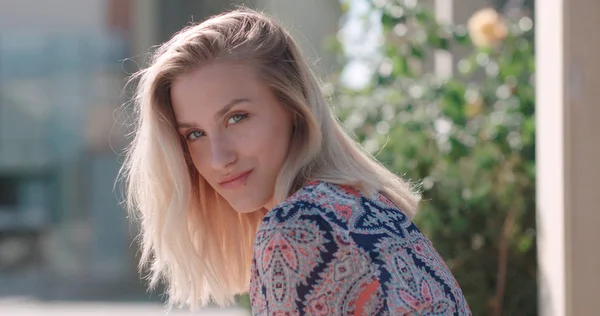 Retrato de una hermosa chica rubia mirando a la cámara y sonriendo, al aire libre . — Foto de Stock