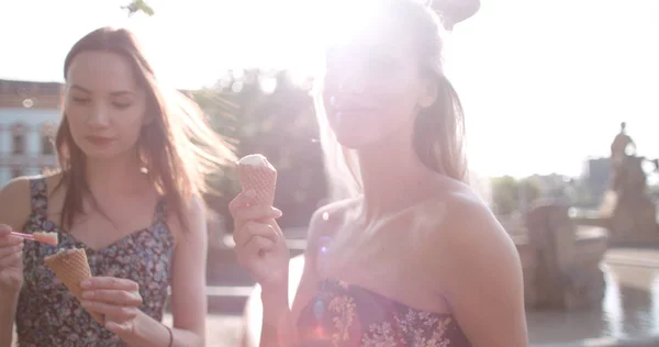 Dos amigas comiendo helado y charlando en la ciudad . — Foto de Stock