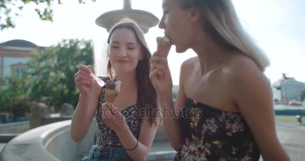 Dos amigas comiendo helado y charlando en la ciudad . — Vídeos de Stock