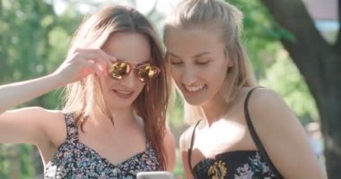 İki genç kız bir şehir parkında istimal hareket eden telefon. 