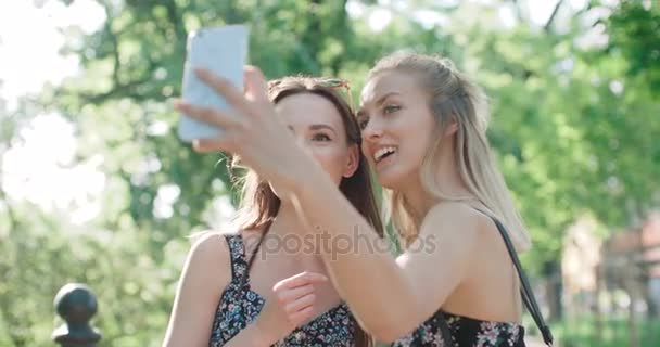 Deux belles adolescentes utilisant le téléphone dans un parc de la ville . — Video