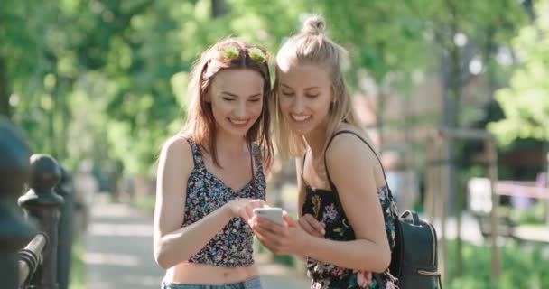 Duas adolescentes usando telefone celular em um parque da cidade . — Vídeo de Stock