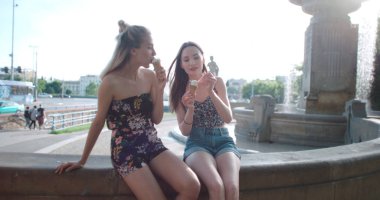 Dondurma yeme ve şehirde chat yapan iki kadın arkadaş. 