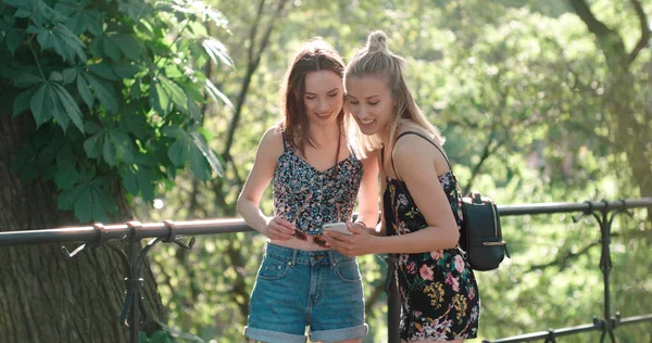 Dos adolescentes usando teléfono móvil en un parque de la ciudad . — Foto de Stock