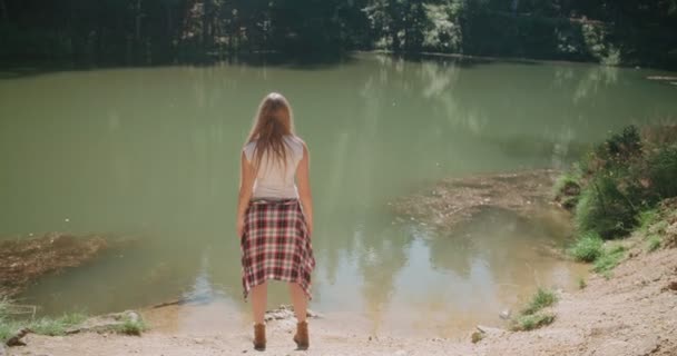 Hermosa chica caucásica pasar tiempo junto a un lago en un bosque . — Vídeos de Stock