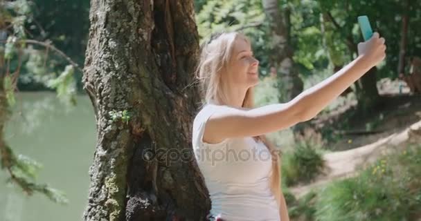 Młoda kobieta biorąc selfie przez smartfon w lesie. — Wideo stockowe