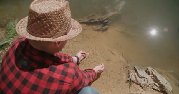 Jongeman dompelen handen in lake. — Stockvideo