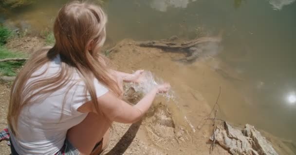 Jonge vrouw dompelen handen in lake. — Stockvideo