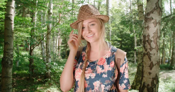 Retrato de una hermosa mujer caucásica en un bosque con sombrero y mochila . — Foto de Stock
