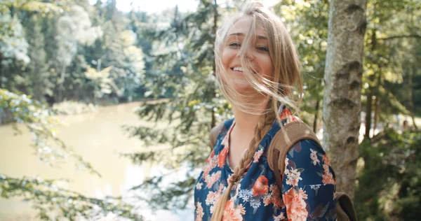 Aventura, viajes, turismo y ocio concepto - chica sonriente relajarse junto al lago en el bosque . — Foto de Stock