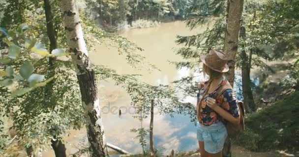 Πορτρέτο του όμορφη γυναίκα Καυκάσιος μέσα σε ένα δάσος φορώντας καπέλο και σακίδιο. — Αρχείο Βίντεο