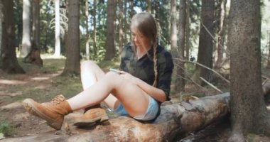 Bir ormanda bir akıllı telefon kullanan genç kadın.