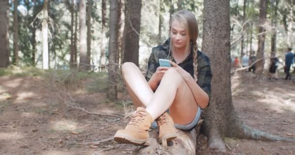 Ung kvinna med en smartphone i en skog. — Stockvideo