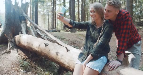 Amar joven pareja caucásica tomando autorretrato en un bosque . — Vídeo de stock