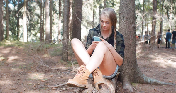 Bir ormanda bir akıllı telefon kullanan genç kadın.