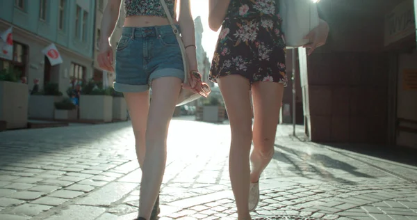 Unerkennbares Porträt zweier hagerer Mädchen, die auf einer Straße in der Stadt spazieren gehen. — Stockfoto