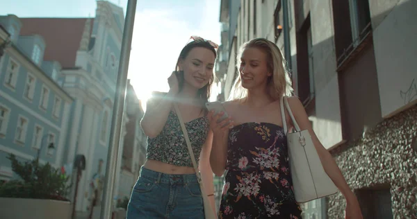 Dos chicas alegres discutiendo las últimas noticias de chismes en una ciudad . — Foto de Stock