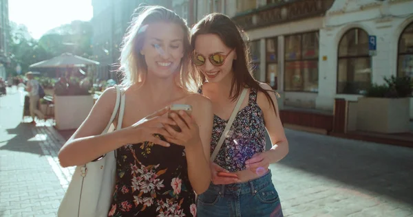 Lindas jovens mulheres assistindo fotos em um telefone . — Fotografia de Stock