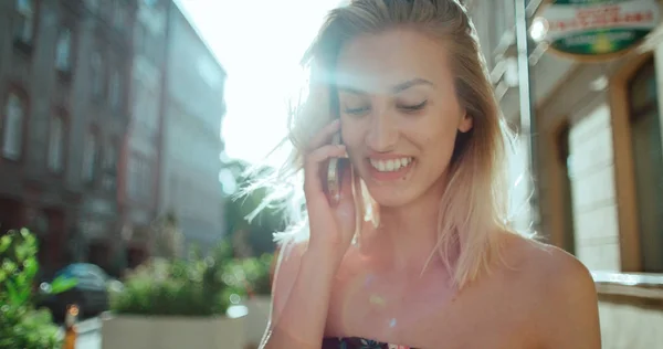 Piękna młoda kobieta rozmawia telefon w słoneczny dzień. — Zdjęcie stockowe