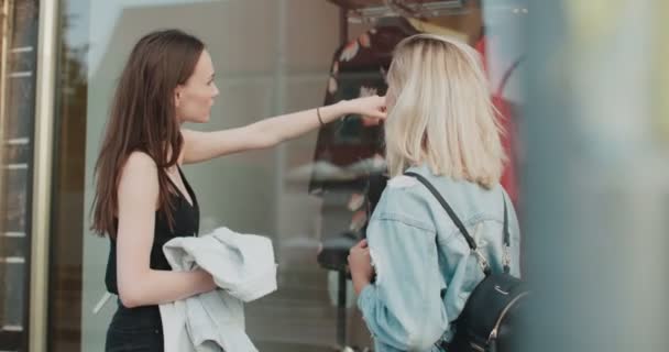 Duas meninas bonitas olhando para roupas em uma vitrine . — Vídeo de Stock