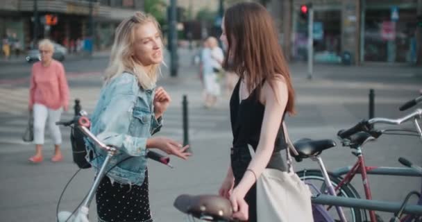 Zwei fröhliche Mädchen diskutieren in einer Stadt über die neuesten Klatschnachrichten. — Stockvideo