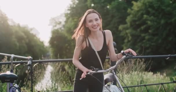 Portret van vrolijk lachende jonge vrouw met fiets op een straat. — Stockvideo