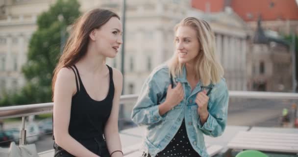 Dos chicas alegres discutiendo las últimas noticias de chismes en una ciudad . — Vídeos de Stock