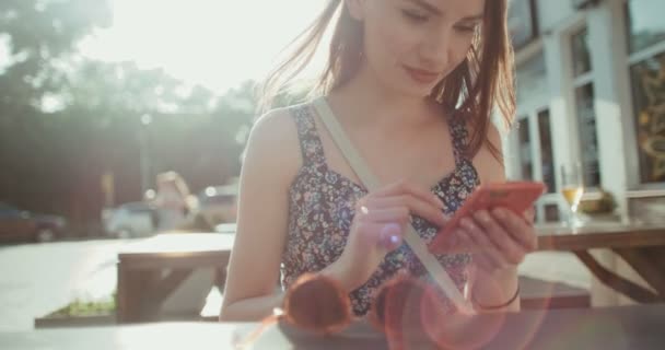 Beautiful young woman typing on phone in a city street. — Stock Video