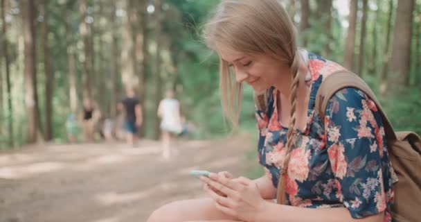 Mujer joven usando un smartphone en un bosque . — Vídeo de stock