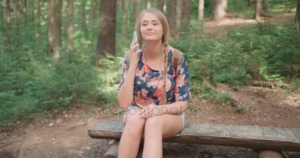 숲에서 전화로 얘기 하는 젊은 여자. — 비디오