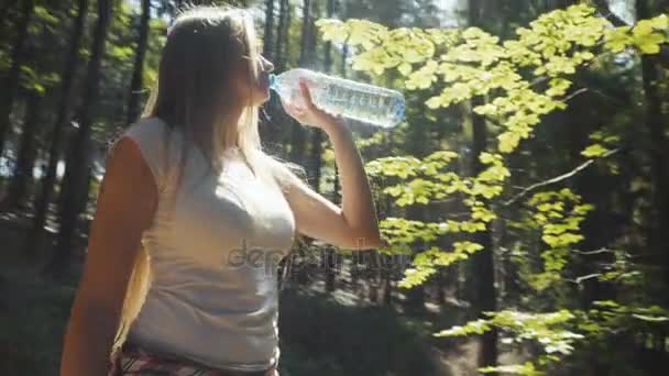 Mujer joven bebiendo agua al aire libre en el soleado parque o bosque . — Vídeo de stock