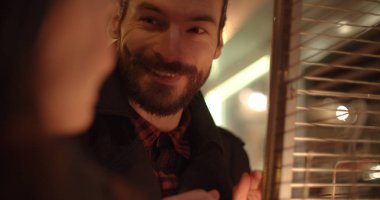Açık şöminenin yanında ısınma aşık genç bir çift. Genç güzel bir şehirde gece tarihte Çift.