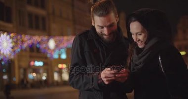 Geceleri Smartphone kullanarak genç mutlu çift. Genç güzel çift anılar ve sosyal medya resimleri paylaşmak online mobil uygulaması ile.