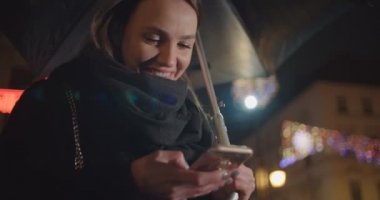 Smartphone bir şehirde geceleri kullanan genç kadın. Smartphone ve mesaj atıp tutan gece şehirde güzel kadın.