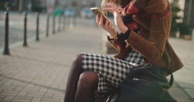 Güzel genç kadın telefonla güneşli gün boyunca yazarak.