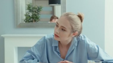 Bir tablo savunarak oturan genç bir çift. Kadın sinirli çünkü adam ona dinlemiyor, telefonunu izliyor.