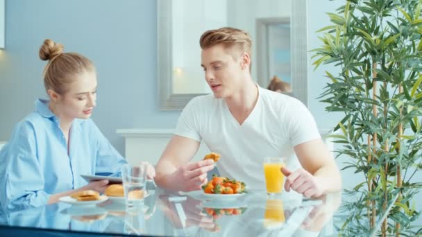 Pareja Joven Usando Tableta Digital Mientras Desayuna Mesa Cocina — Vídeo de stock