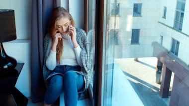 pencerenin yanındaki telefonda konuşan kadın.