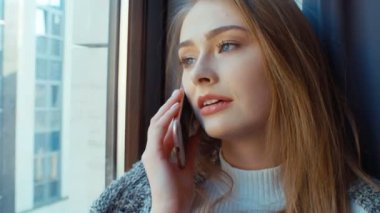 pencerenin yanındaki telefonda konuşan kadın.