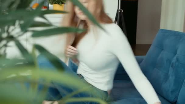 自宅のソファーに座りながらタブレット コンピューターを使用して若い女性 — ストック動画