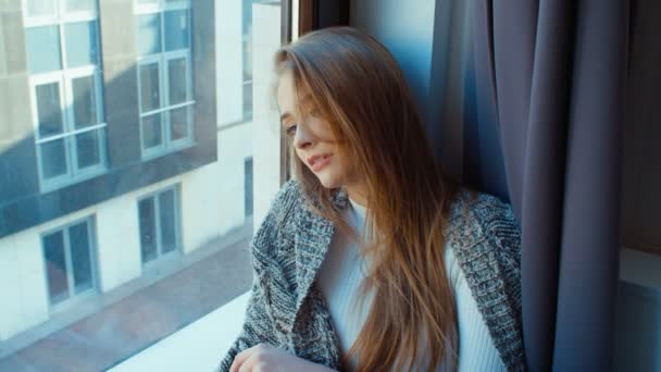 坐在窗边的年轻沉思的女人 一个美丽的女孩在家里的肖像 — 图库视频影像