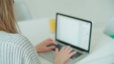 Masada otururken dizüstü bilgisayar kullanan genç sarışın kadın. Masada otururken dizüstü bilgisayar kullanan genç sarışın kadın.