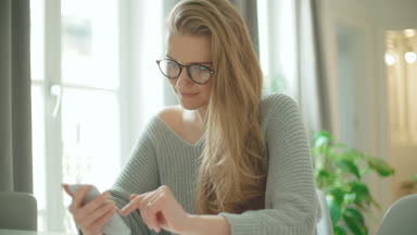 Genç gülümseyen kadın evde telefon kullanma.