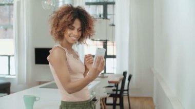 Selfie mutfakta yapma çekici genç siyah kadın. Mutfakta ayakta ve selfie yapım uzun kıvırcık saçlı çekici genç siyah kadın.