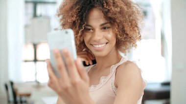 Selfie mutfakta yapma çekici genç siyah kadın. Mutfakta ayakta ve selfie yapım uzun kıvırcık saçlı çekici genç siyah kadın.