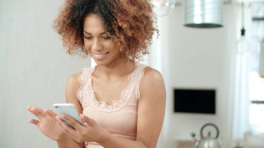 Güzel genç afro Amerikalı kadın cep telefonu evde kullanma.