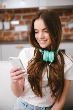 Evde akıllı telefon kullanan genç bir kadın..