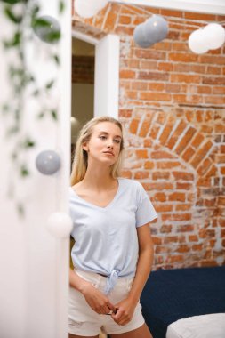 Sarışın genç bir kadın evde aynaya bakıyor..