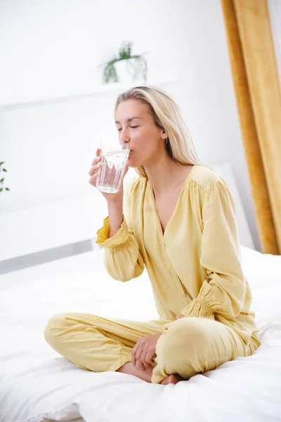 Junge Frau Sitzt Morgens Mit Glas Wasser Auf Ihrem Bett — Stockfoto