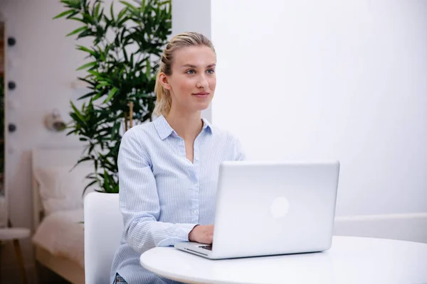 Young blonde woman working with computer at home.